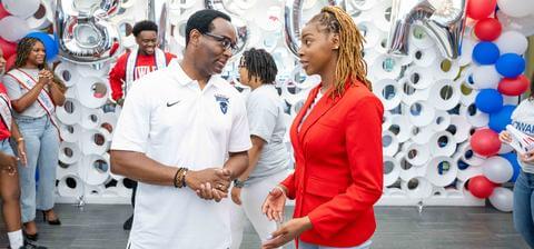 President Ben Vinson, III wearing a white shirt and talking to a student wearing a red blazer.